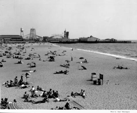 1939 - People relax on the beach in the sun and under umbrellas